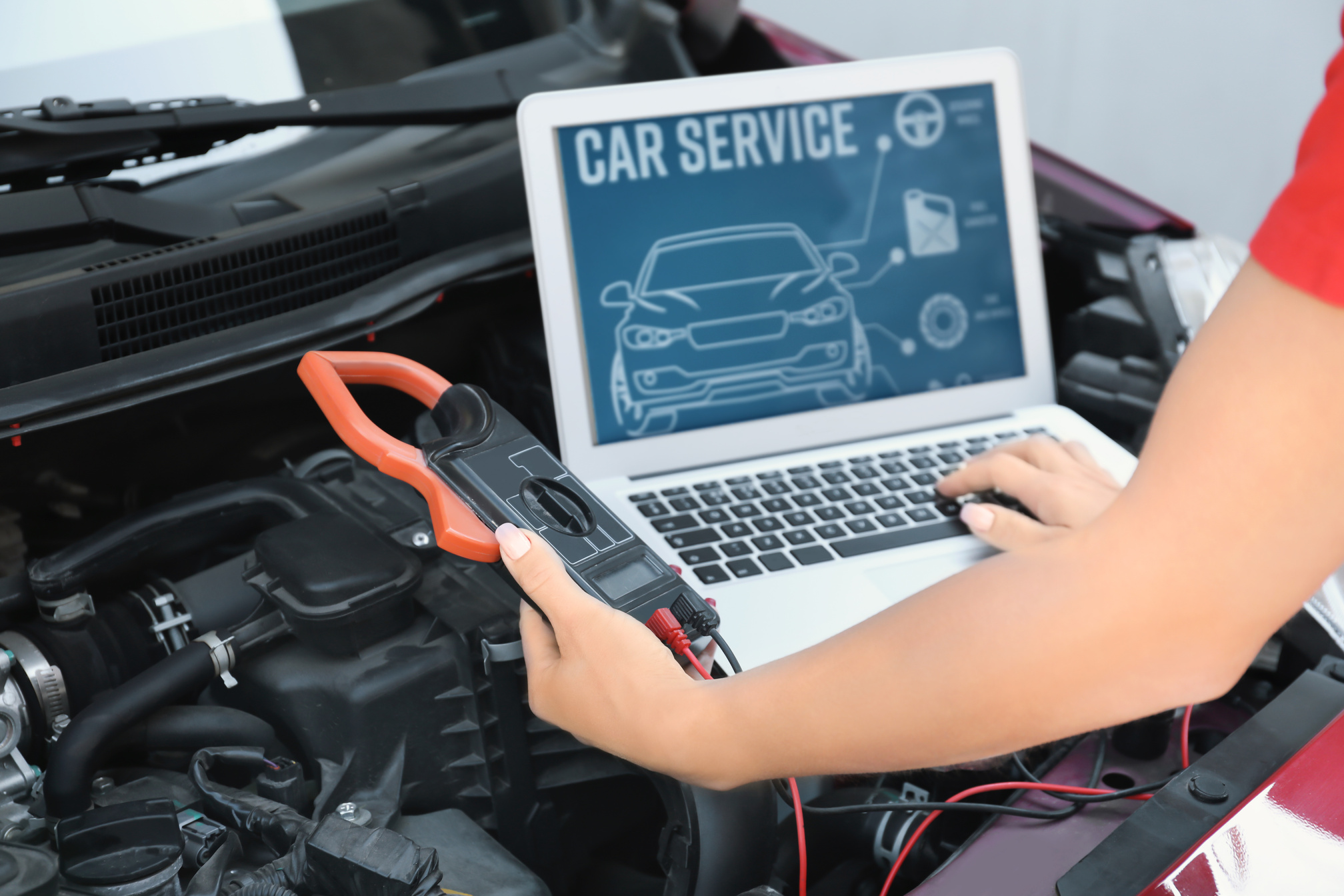 Mechanic with Laptop Repairing Car in Body Shop